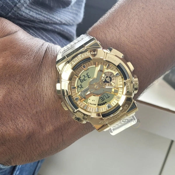 G-shock Referencia: GM-110SG-9ADR Genero: unisex Composición: digital, analogo, cronometro, temporizador, alarma, calendario. Materiales: acero inoxidable y resina Color: transparente y dorado Impermeabilidad: 20 atm Cristal: mineral Producto con garantía de 1 año en funcionamiento. Recomendaciones Reloj con resistencia al agua para sumergirse. No manipular los botones cuando se esté en contacto con el agua